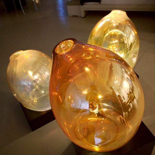 Three glass sculptures on a table with a blurred indoor background