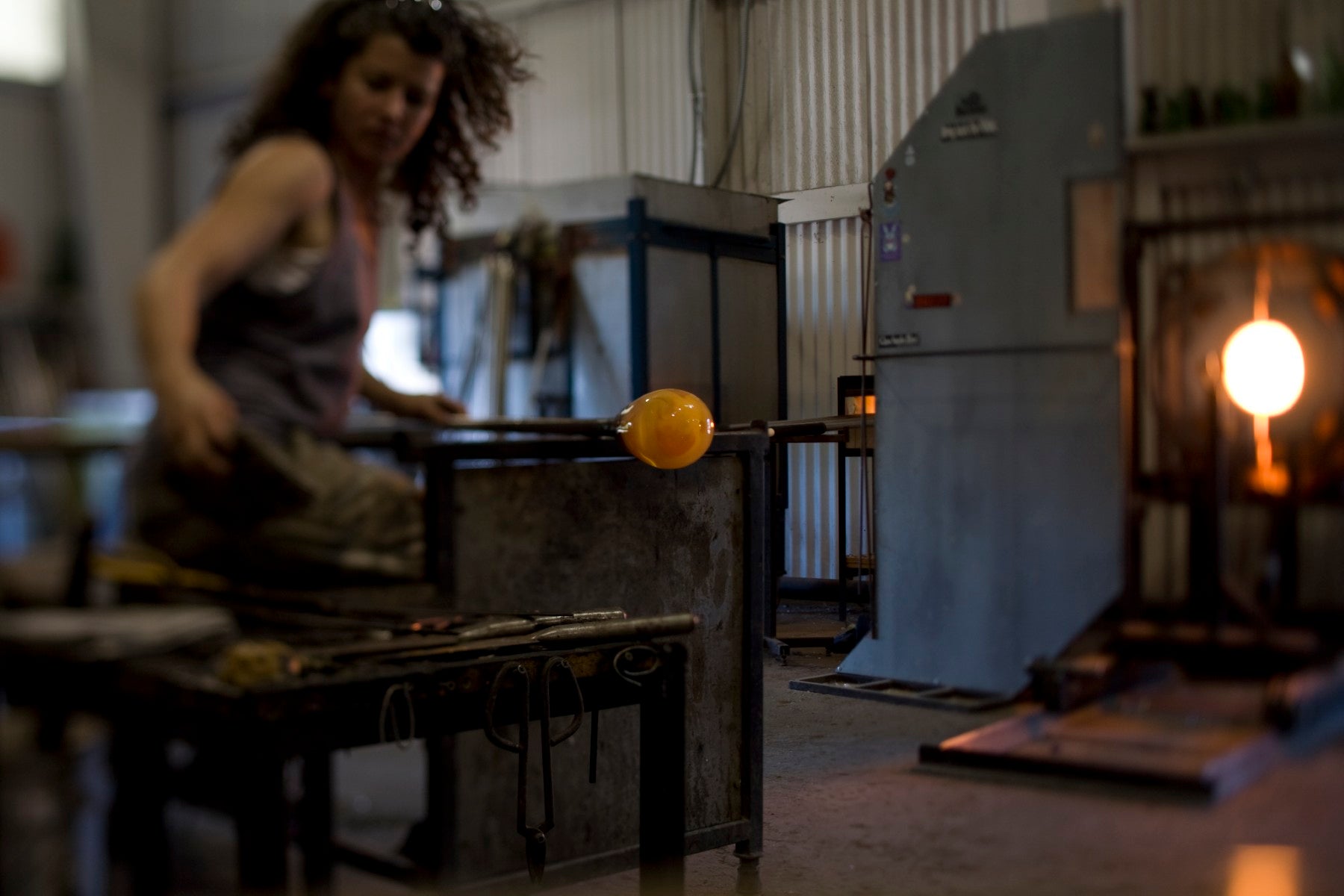 Glassblowing workshop with a glassblower shaping molten glass.